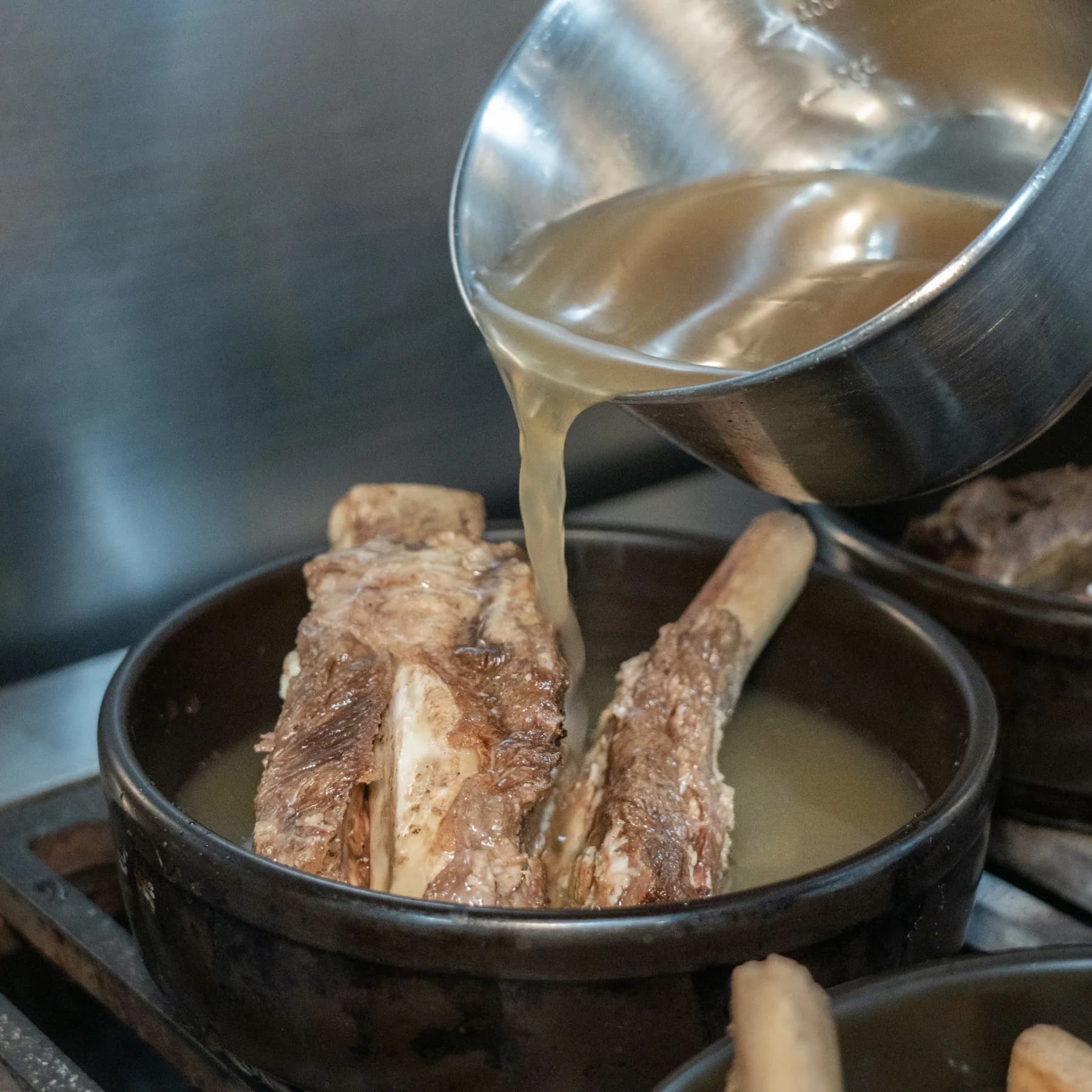 제일면옥 주방에서 갈비탕 뚝배기에 따뜻한 국물을 붓는 모습